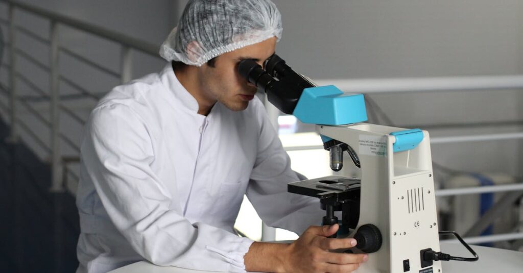 Scientist in a lab coat using a microscope to conduct research, focusing on healthcare improvements.